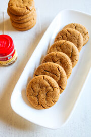 Eggless ginger cookies in a rectangle plate with a stack of cookies in the back.