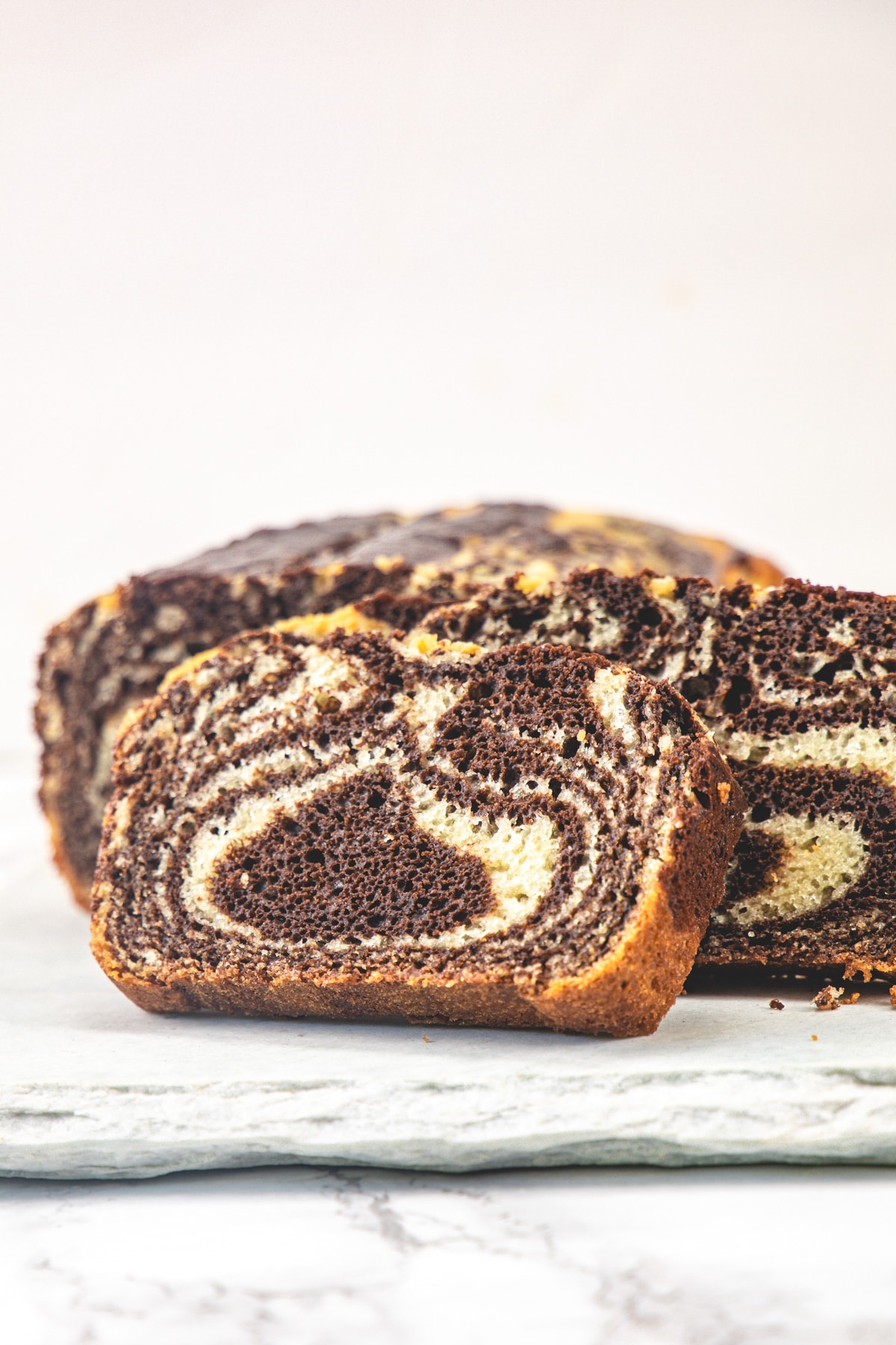 A slice of eggless marble cake on a white board.