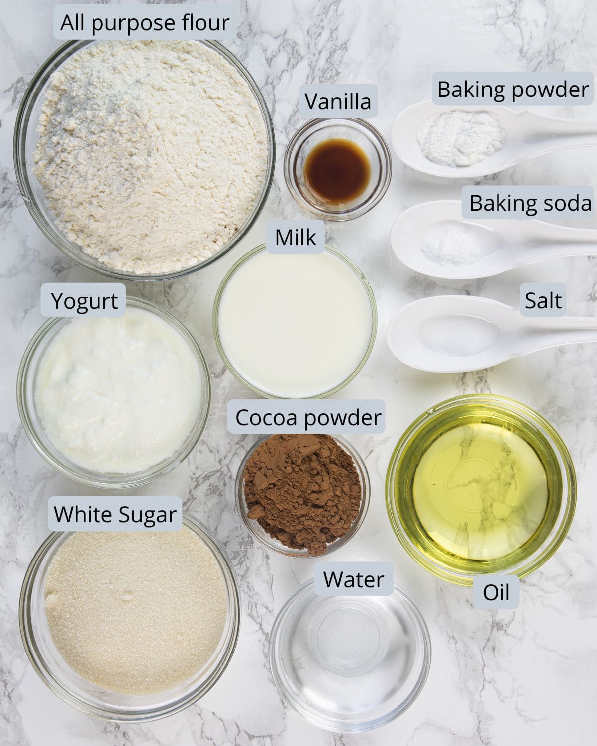 Eggless marble cake ingredients in spoons and bowls with labels.