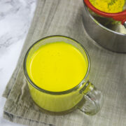 A glass of turmeric mik with napkin under it.