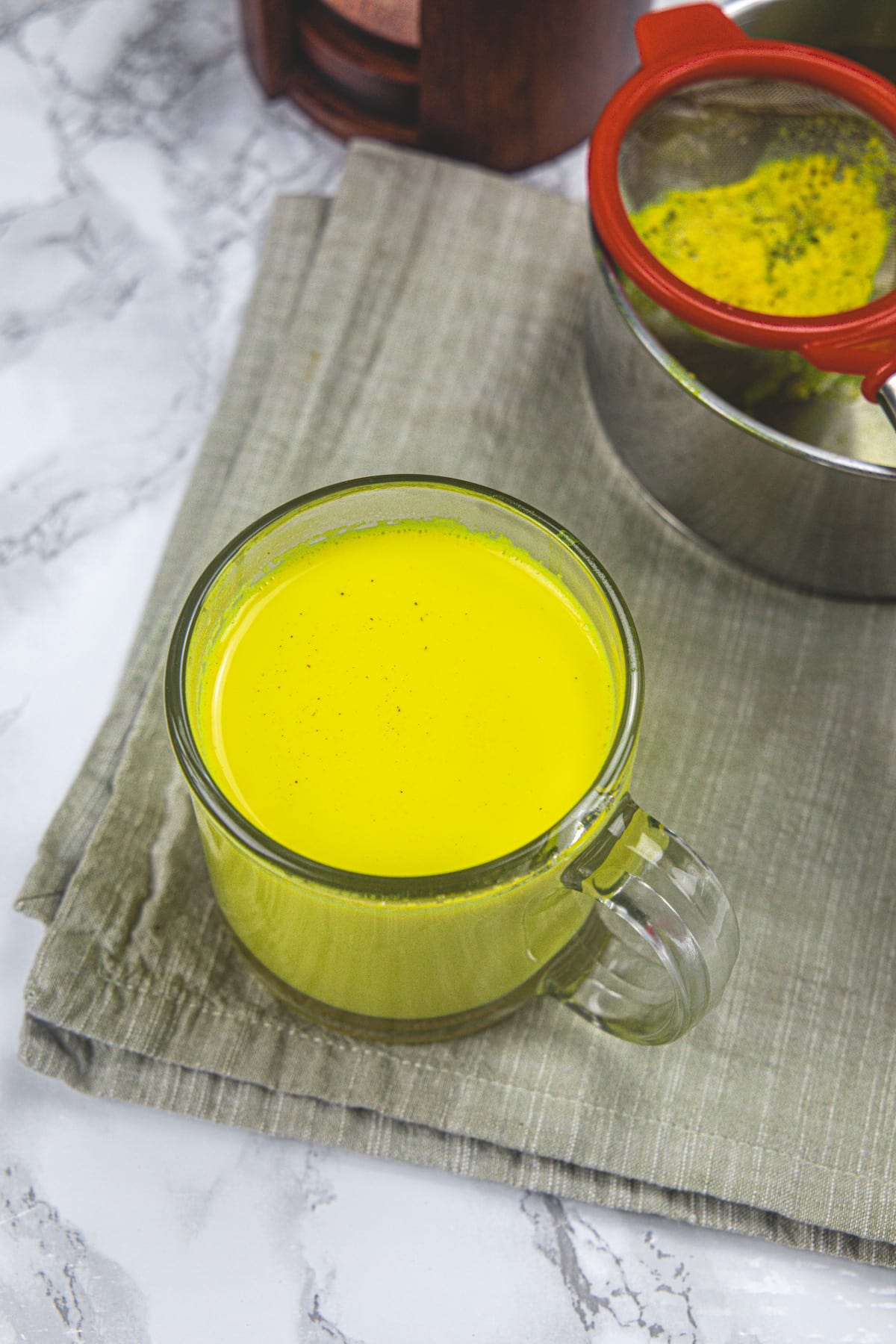 A glass of turmeric mik with napkin under it.