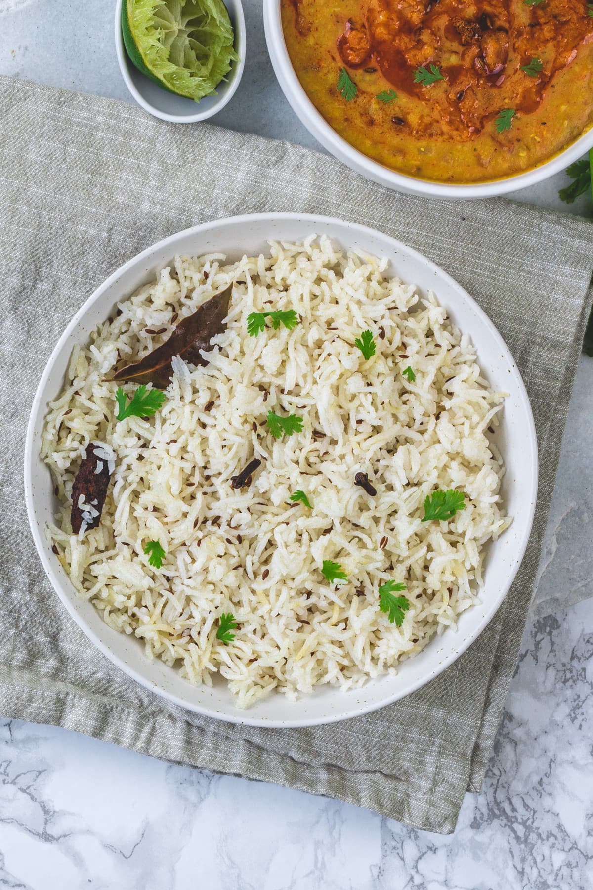 Jeera rice plate with a bowl of dal in the back.