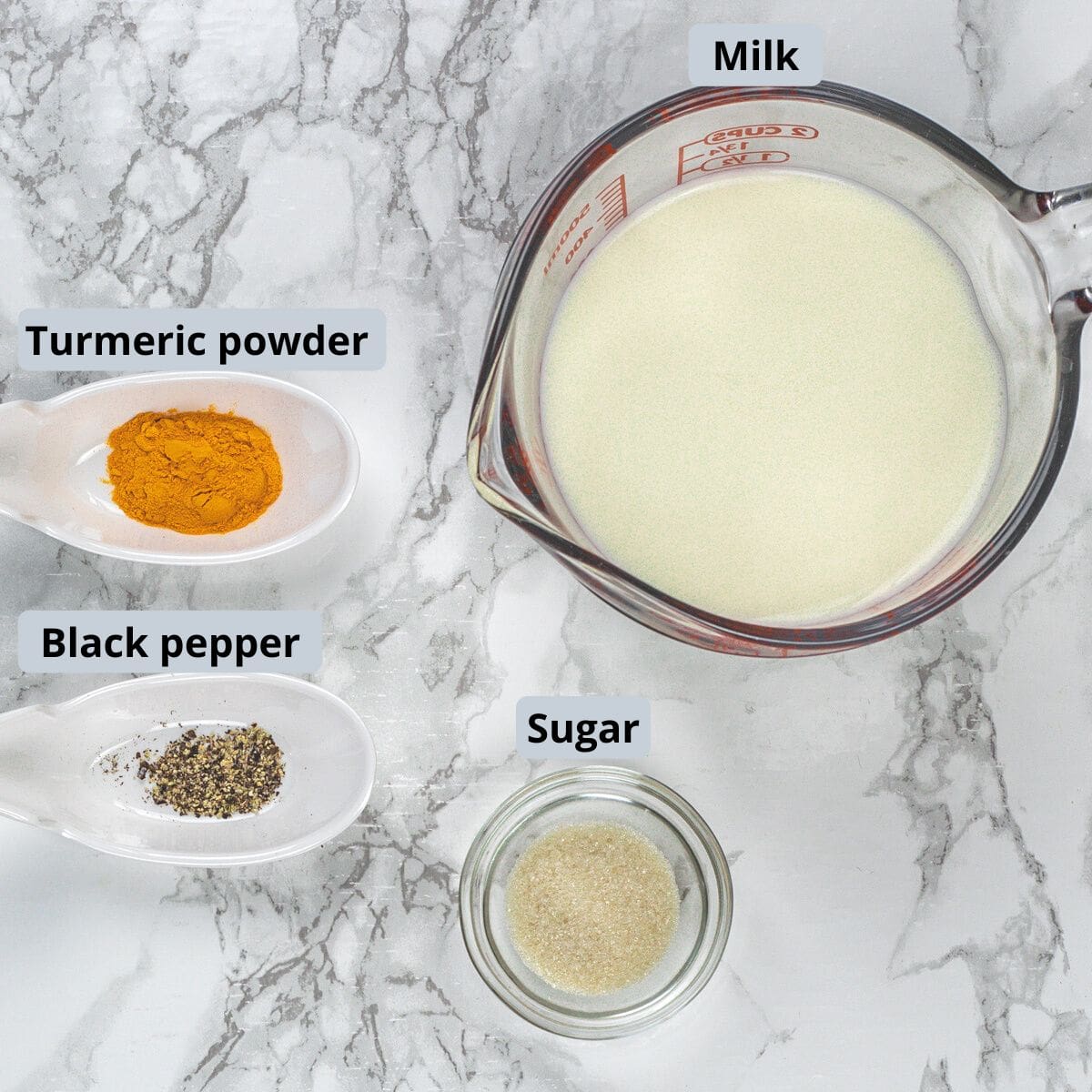 Haldi doodh ingredients in cups and spoons with labels.