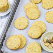 Pistachio cookies in a tray with pistachios on the side.