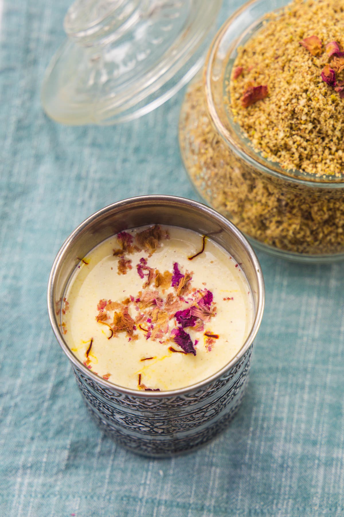 Thandai drink garnished with rose petals and saffron with thandai powder in back.