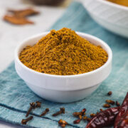 Chana masala powder in a bowl with whole spices around the bowl.