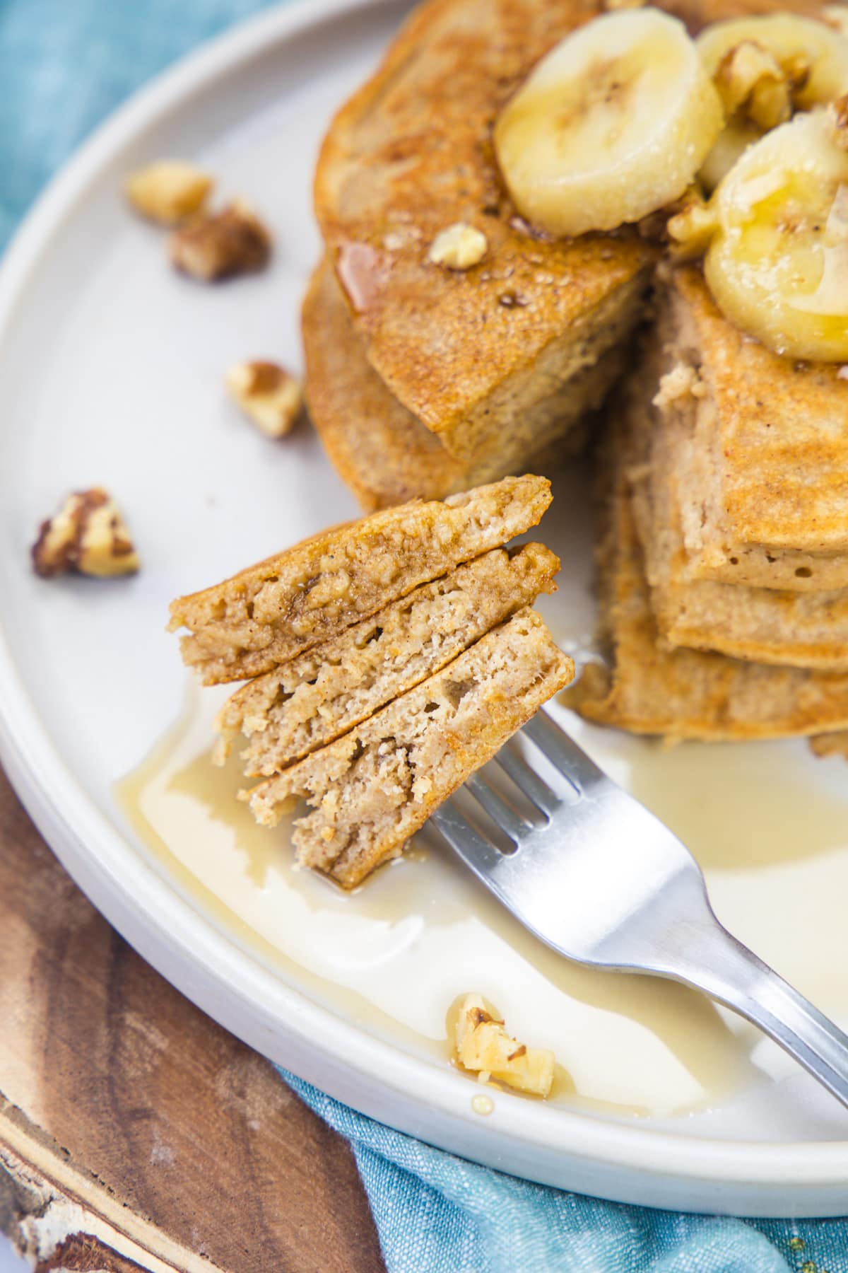 3 pieces of eggless banana pancakes in a fork ready to take a bite.