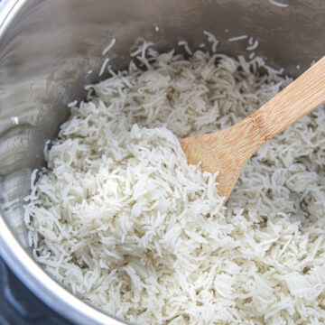 Basmati rice in instant pot with wooden spoon inside.