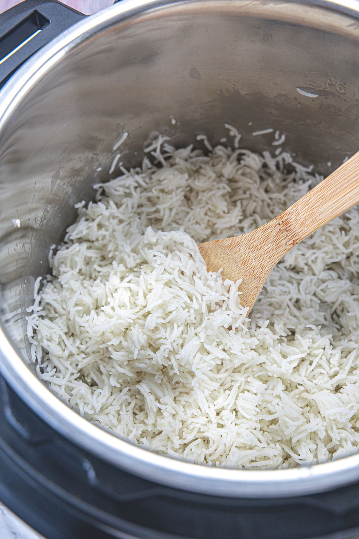 Basmati rice in instant pot with wooden spoon inside.