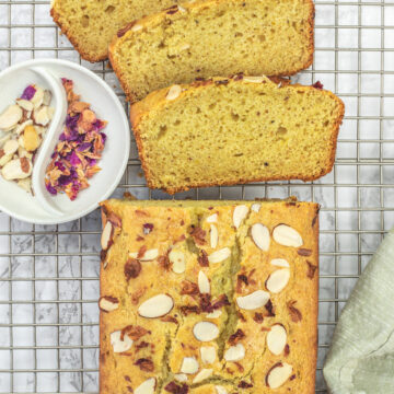 3 slices of thandai cake and rest of the loaf with rose petals and almonds on the side.