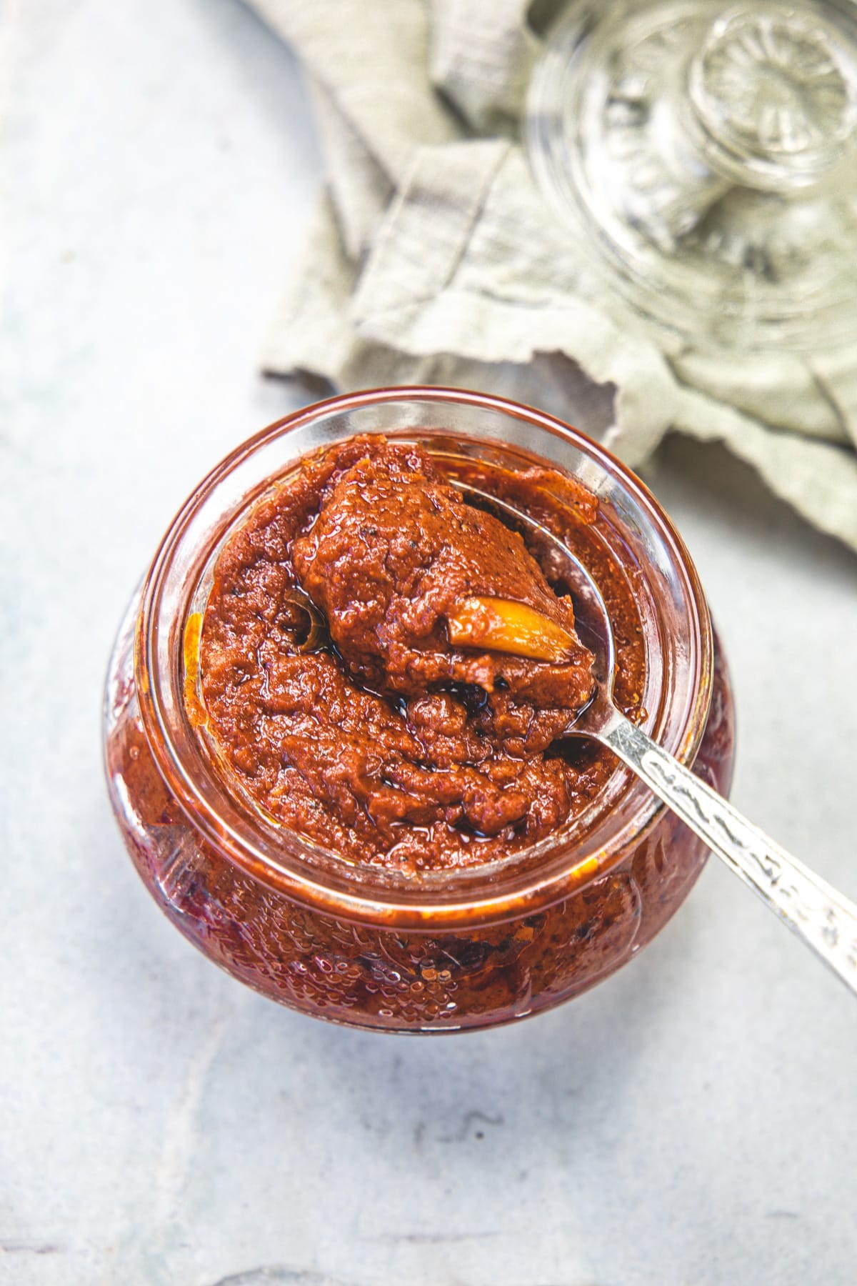 Taking a spoonful of tomato pickle from a jar.