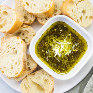 Bread dipping oil in a bowl with bread slices on the side.