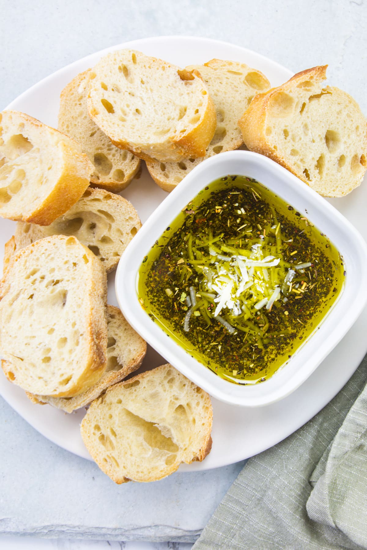 Bread dipping oil in a bowl with bread slices on the side.