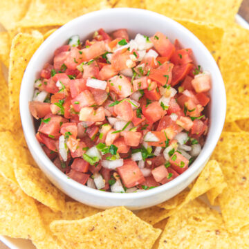 Pico de gallo served in a bowl with tortilla chips on the side.