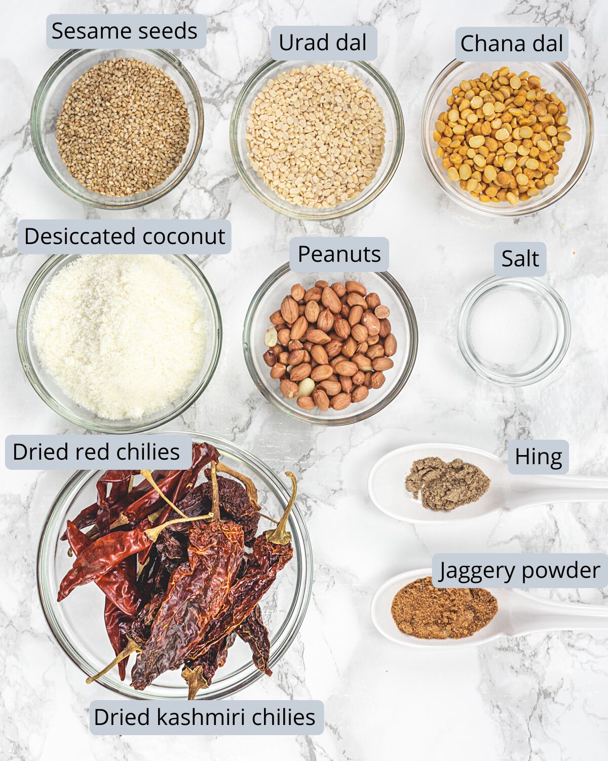 Idli podi ingredients in bowls and spoons with labels.