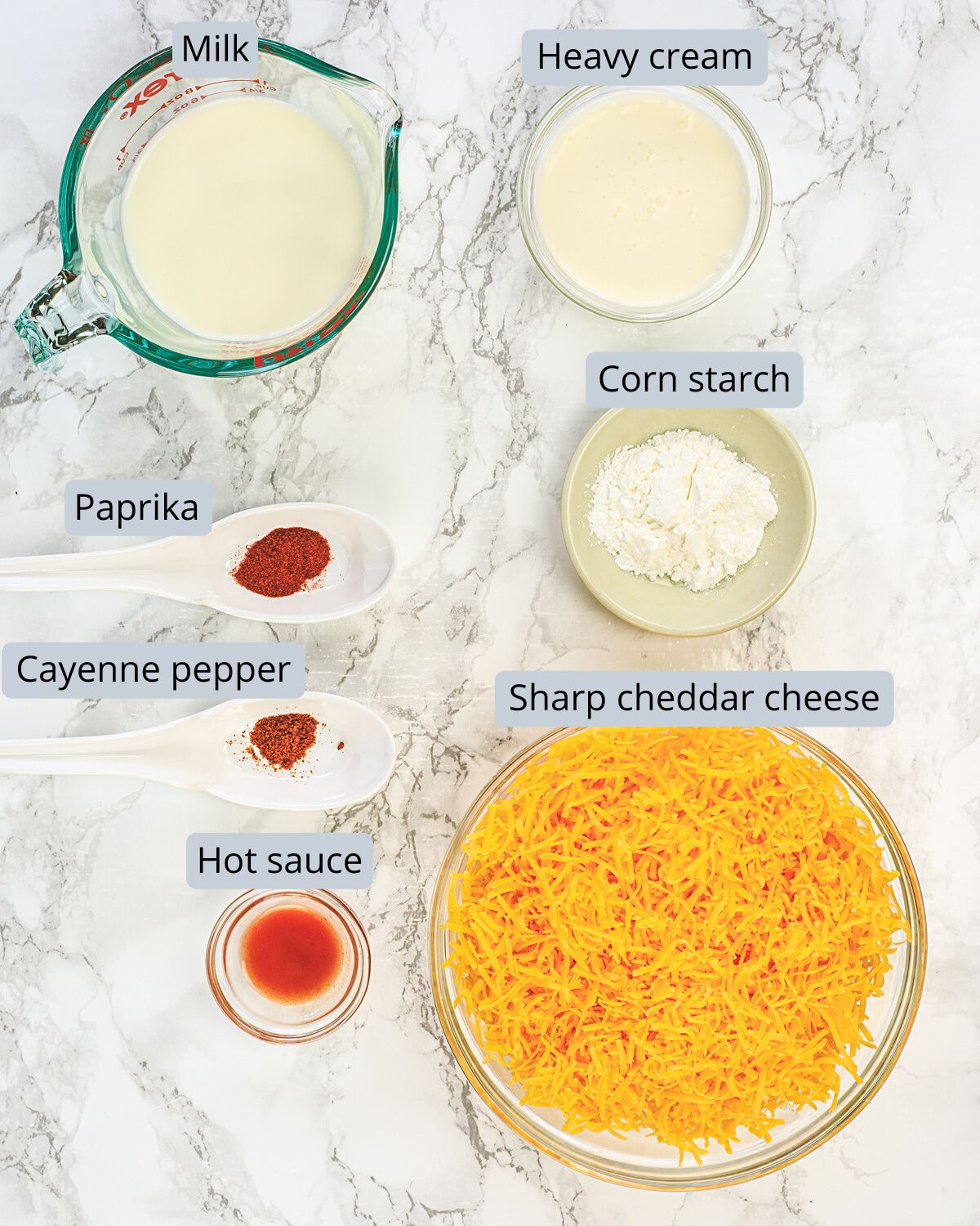 Nacho cheese sauce ingredients in bowls and spoons with labels.