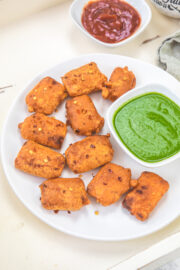 Paneer pakora served with green chutney and ketchup.