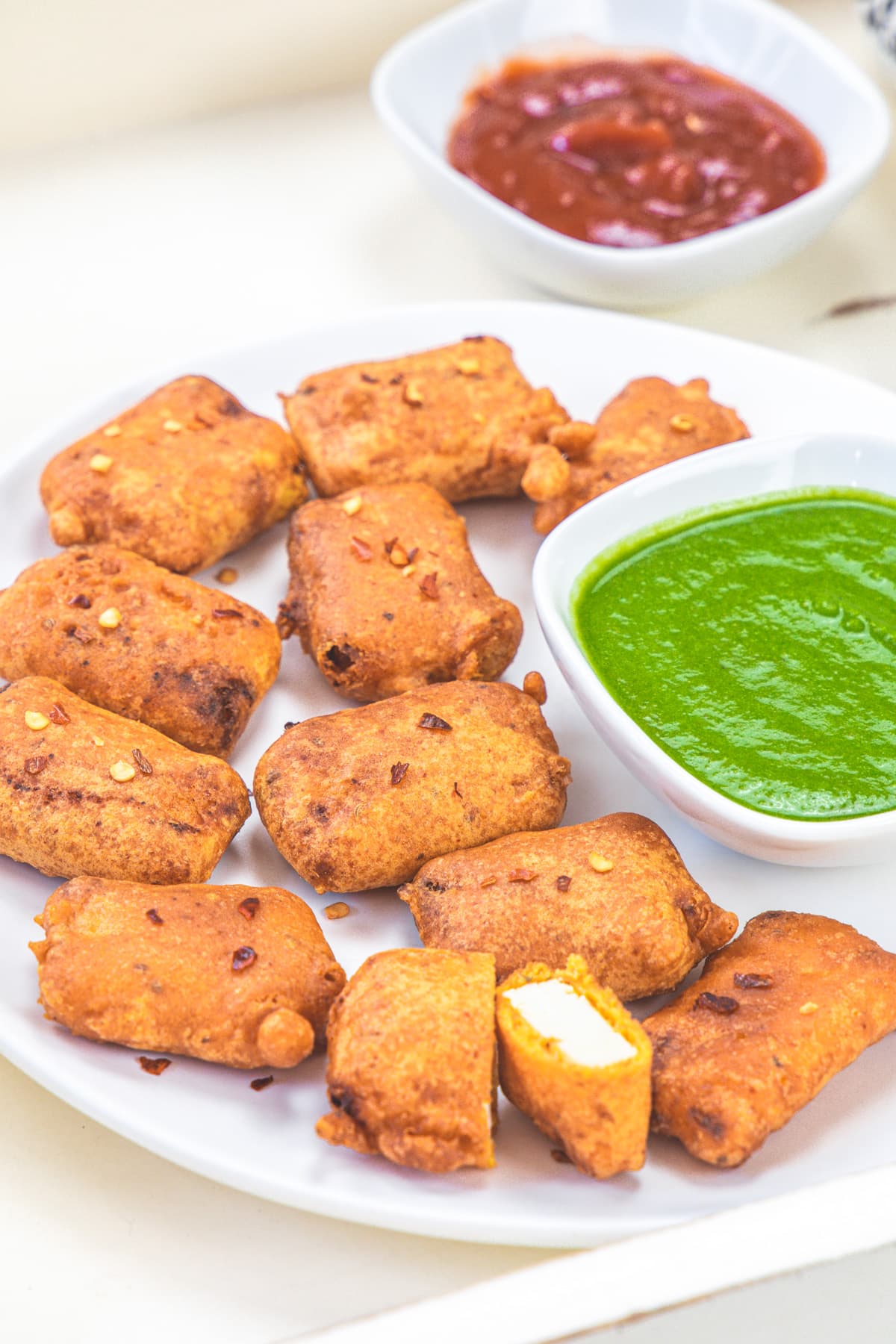 Paneer pakora with cilantro chutney and ketchup bowl in the back.