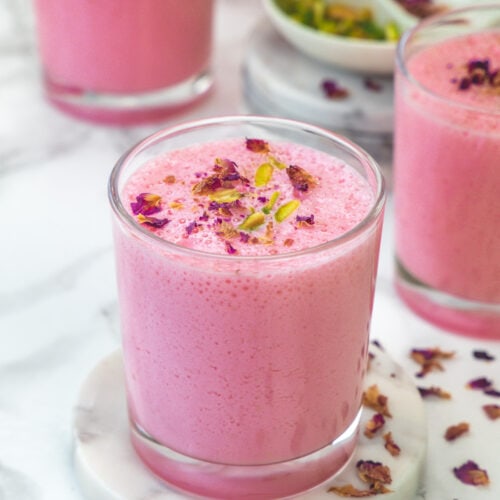 3 glasses of rose lassi with rose petals on the side.