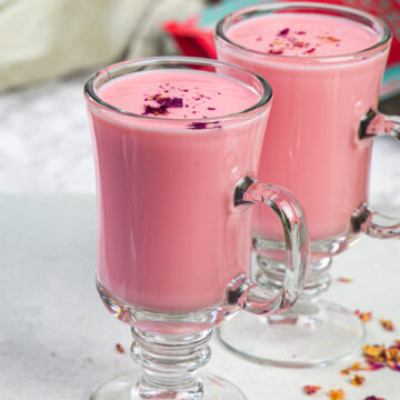 2 glasses of rose milk with napkin and rose petal packet in the back.