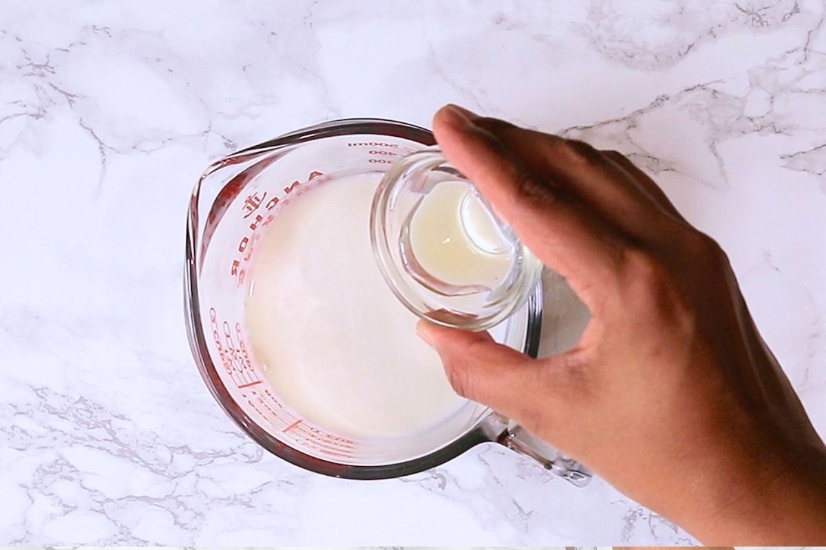Adding vinegar in a cup of milk.