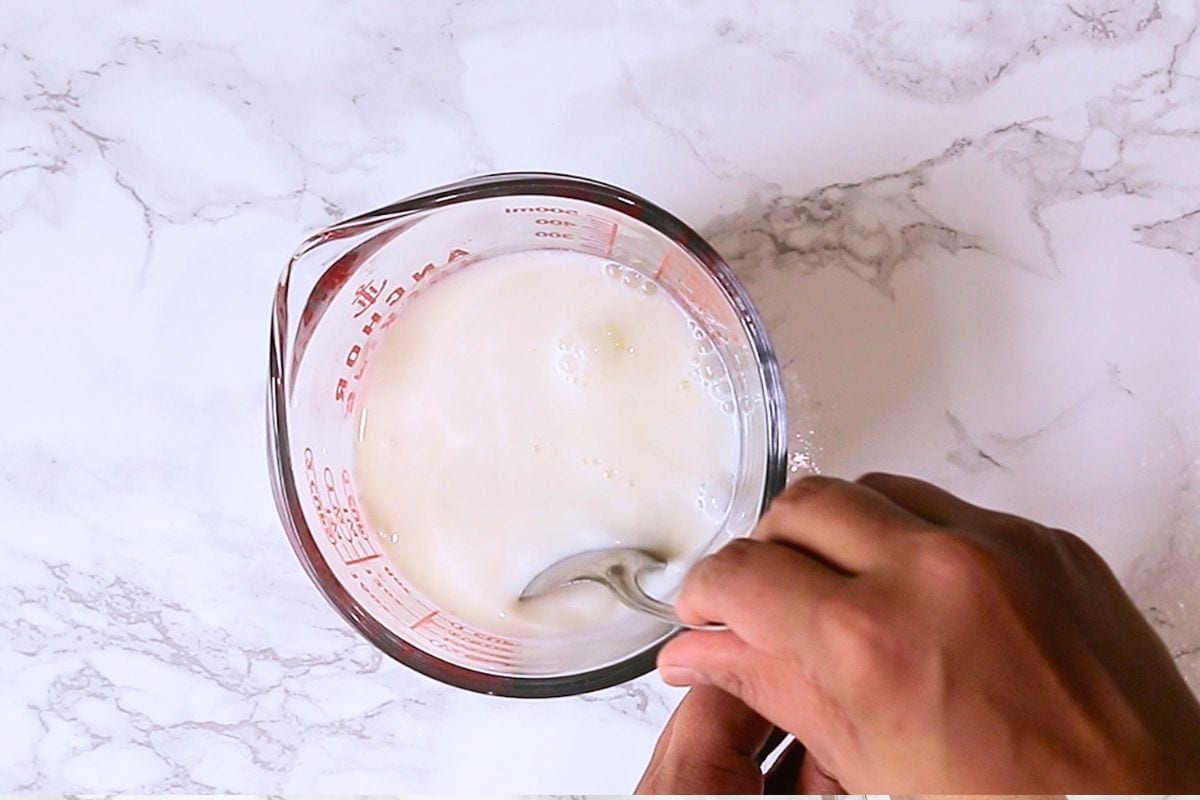 Mixing milk and vinegar mixture in a cup.