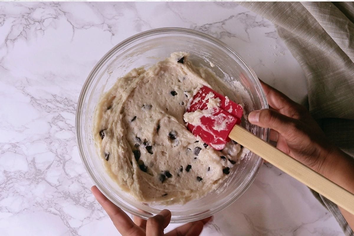 Mixing chocolate chips into muffin batter.