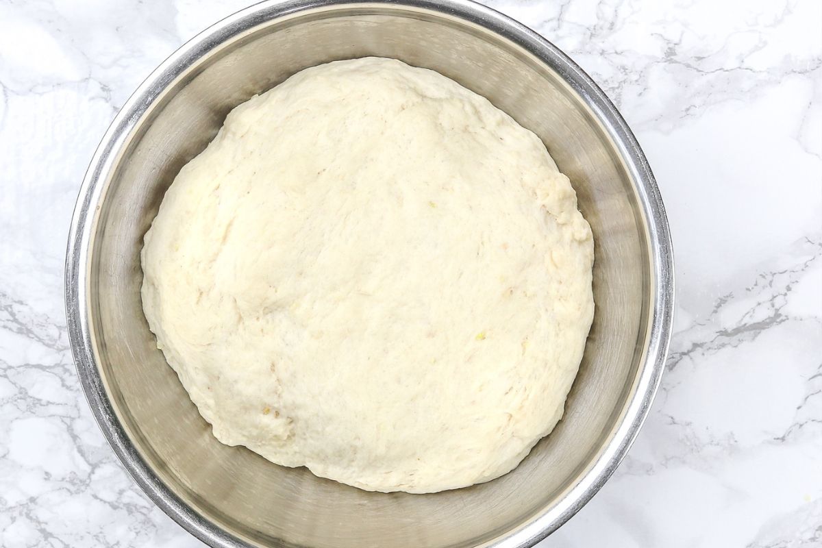 Proofed garlic naan dough in a bowl.