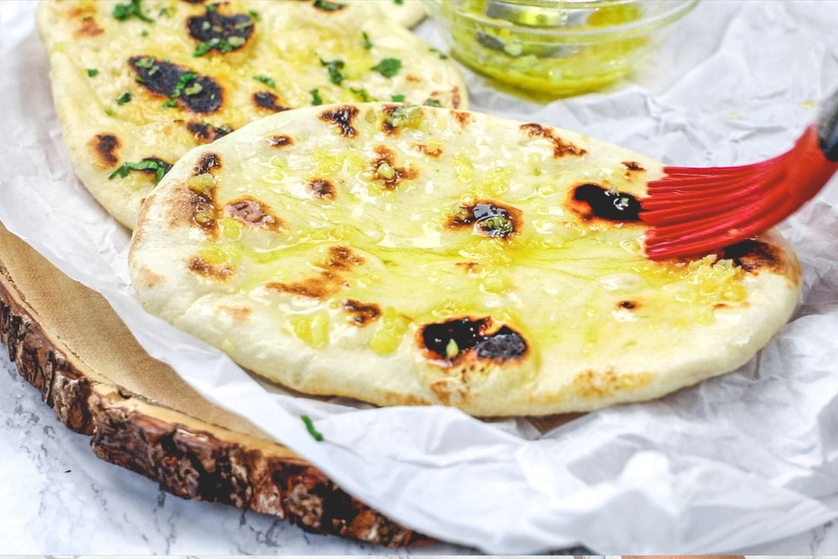 Brushing garlic naan with garlic infused ghee.
