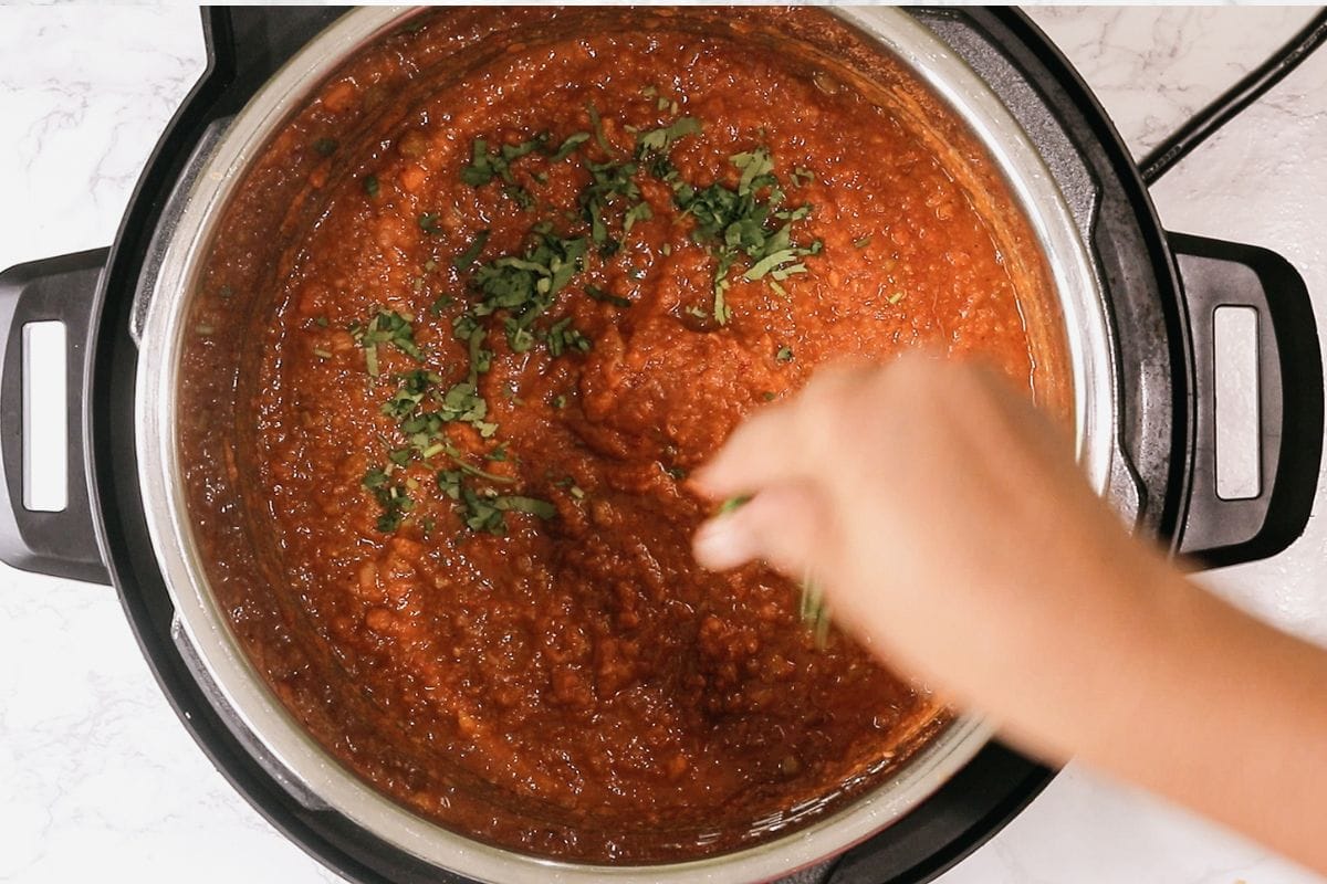Adding cilantro to bhaji.