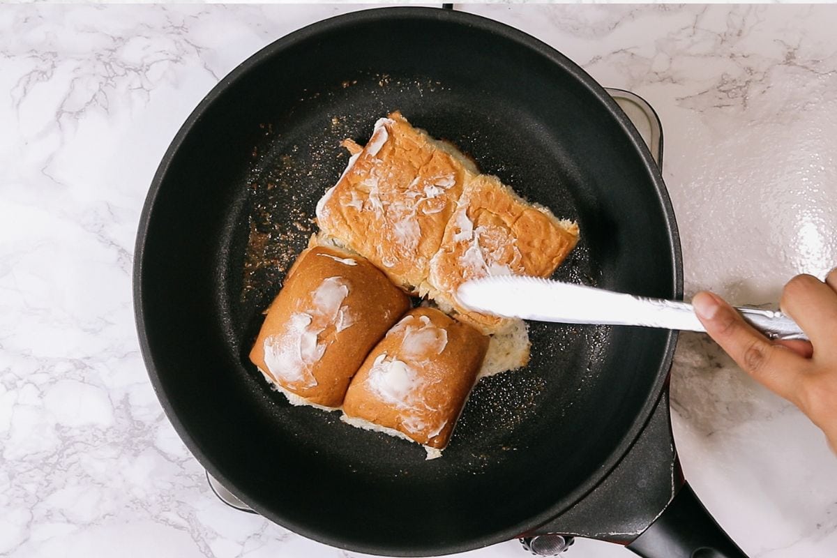 Applying butter on top of the pav.