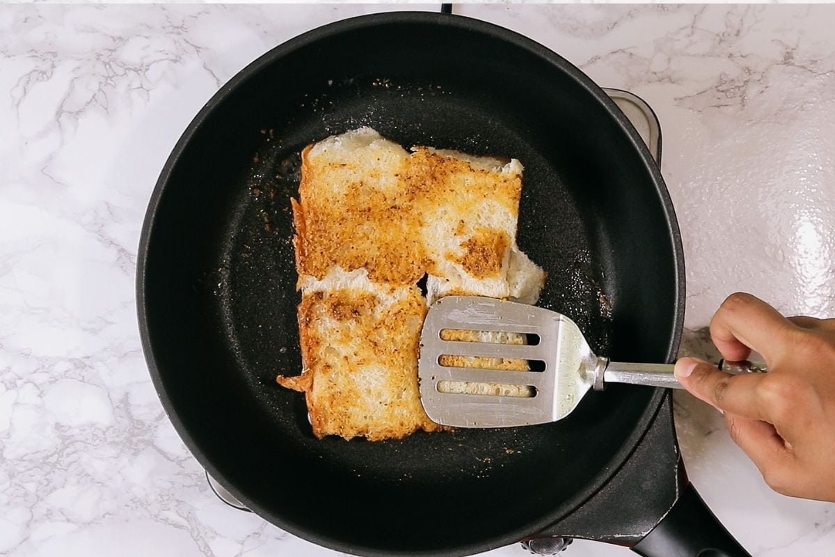 Toasting ladi pav by pressing with spatula.