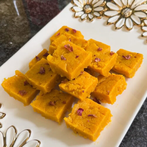 A stack of mango burfi in a white gold plate.
