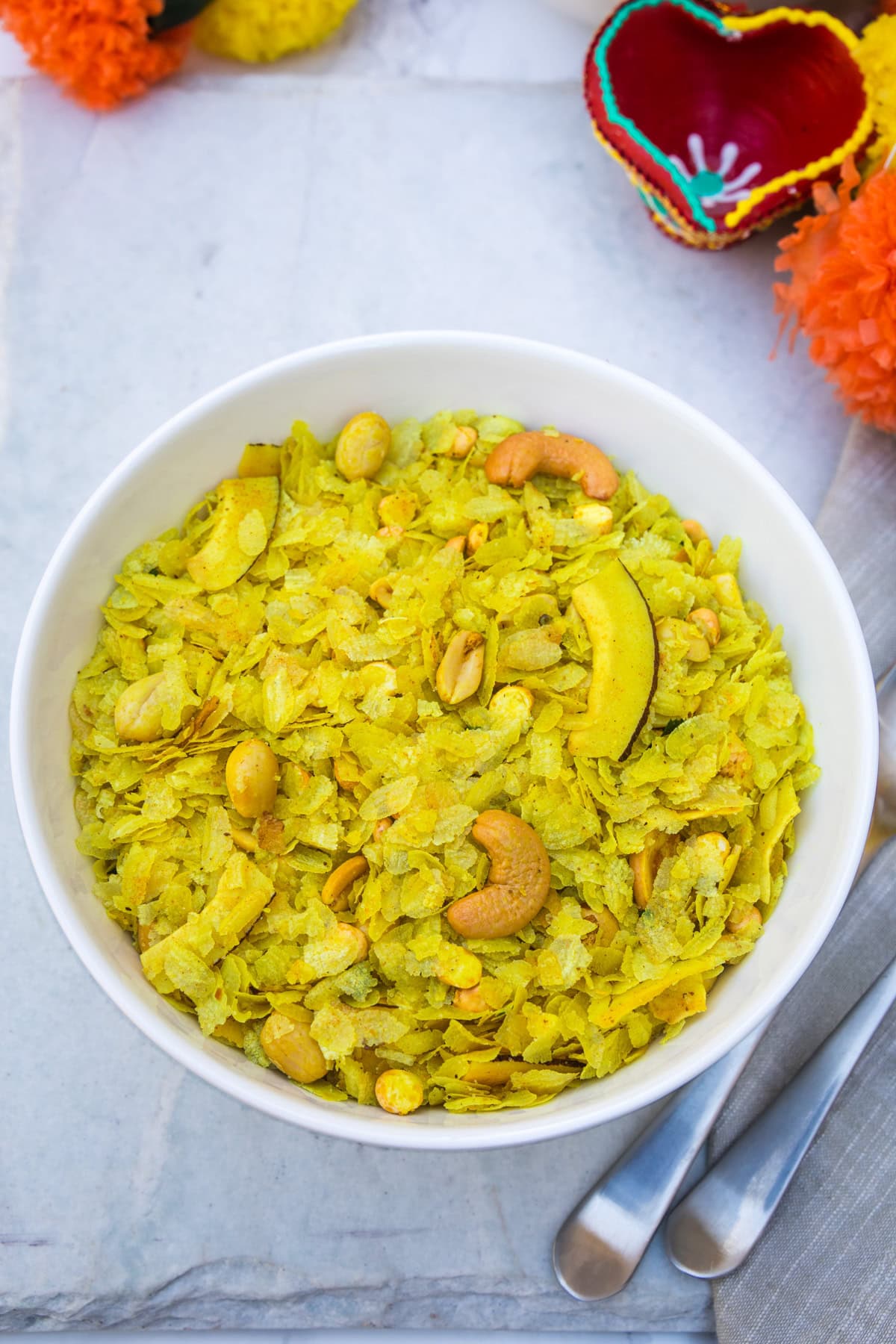 A bowl of thin poha chivda with spoons on the side.