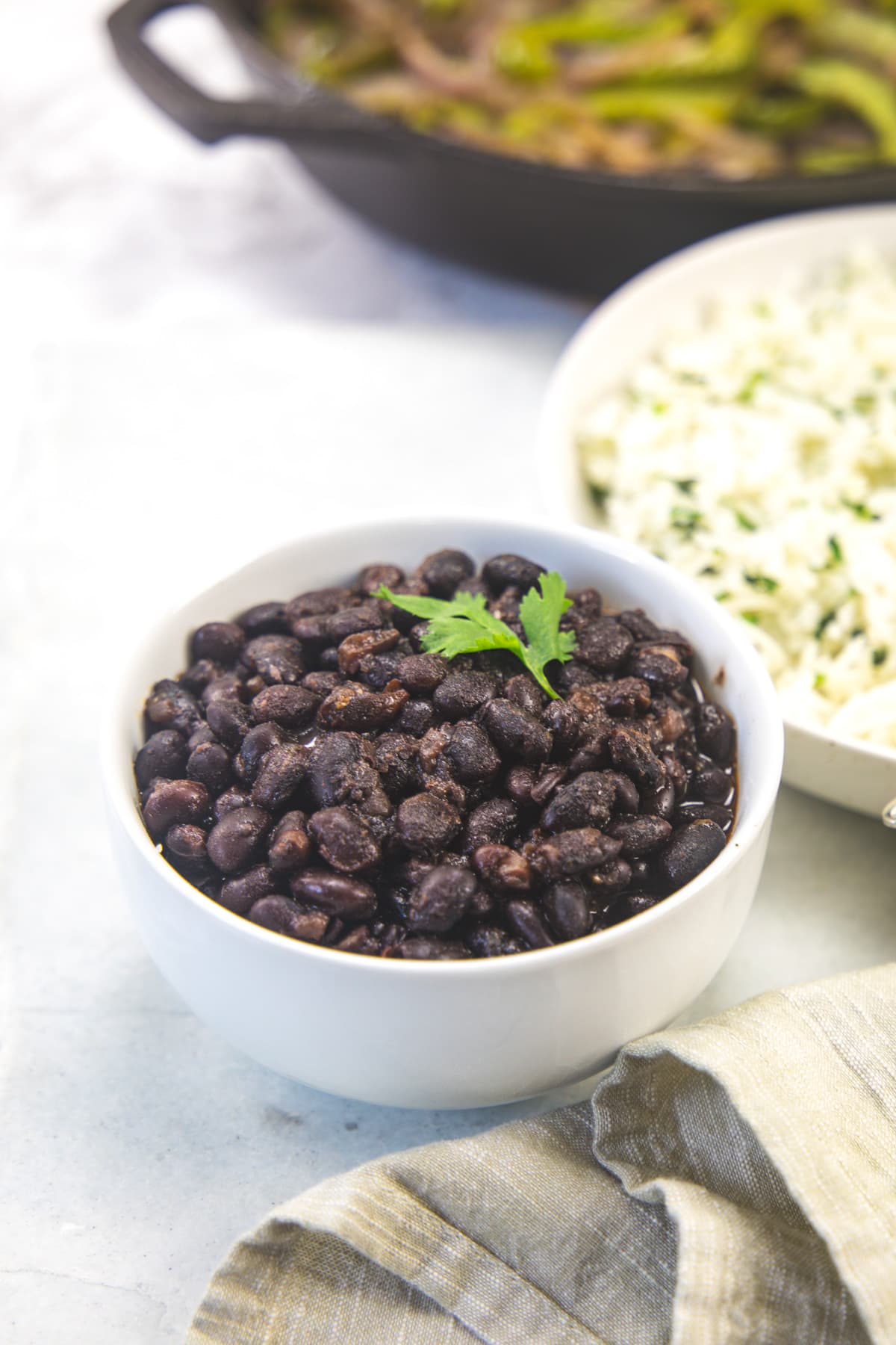 A bowl of copycat chipotle black beans with rice and fajita veggies in the back.