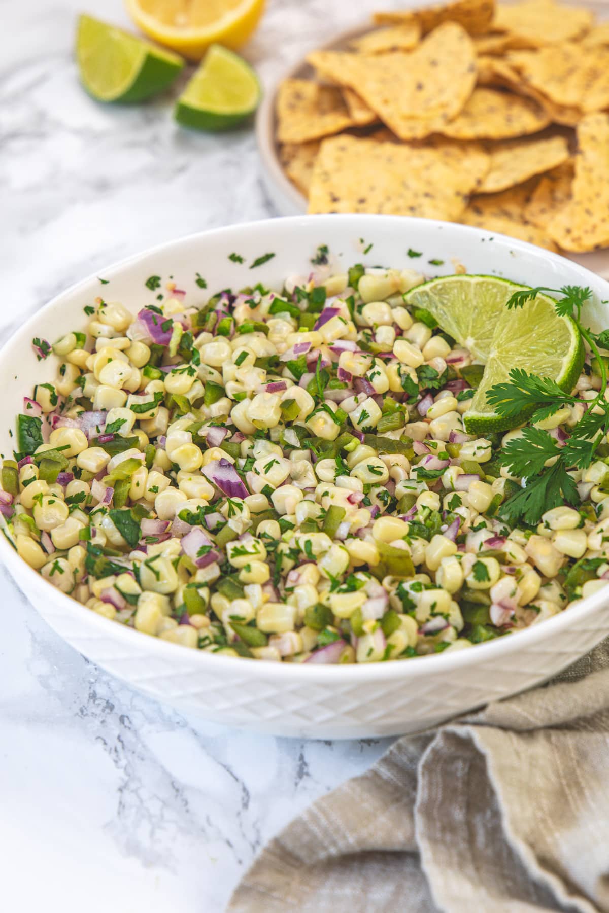 Chipotle corn salsa garnished with lime slices and cilantro, Served with tortilla chips.