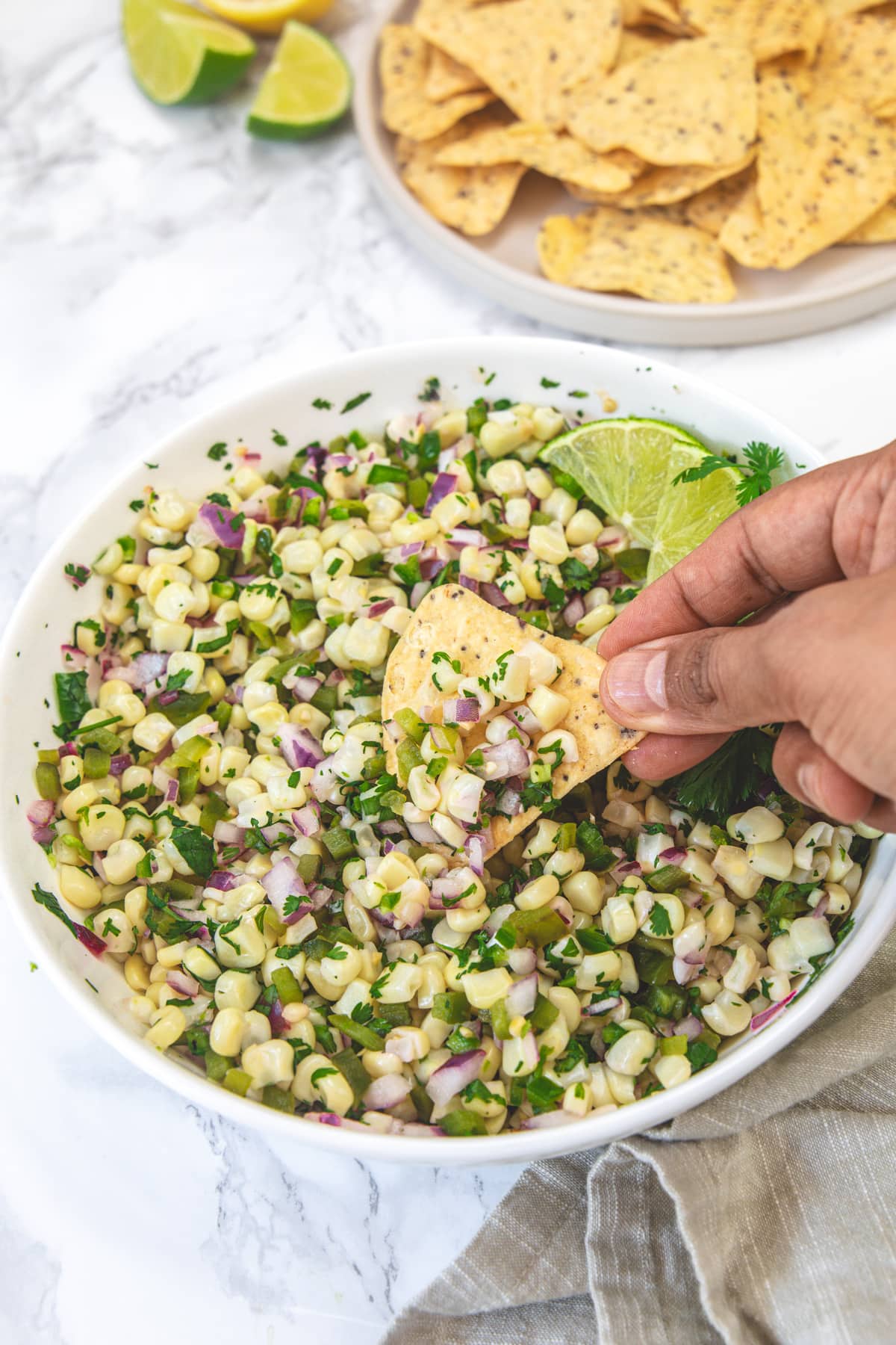 Scooping roasted chili corn salsa with a tortilla chip.