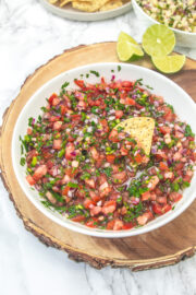 Scooping chipotle fresh tomato salsa with a tortilla chip.