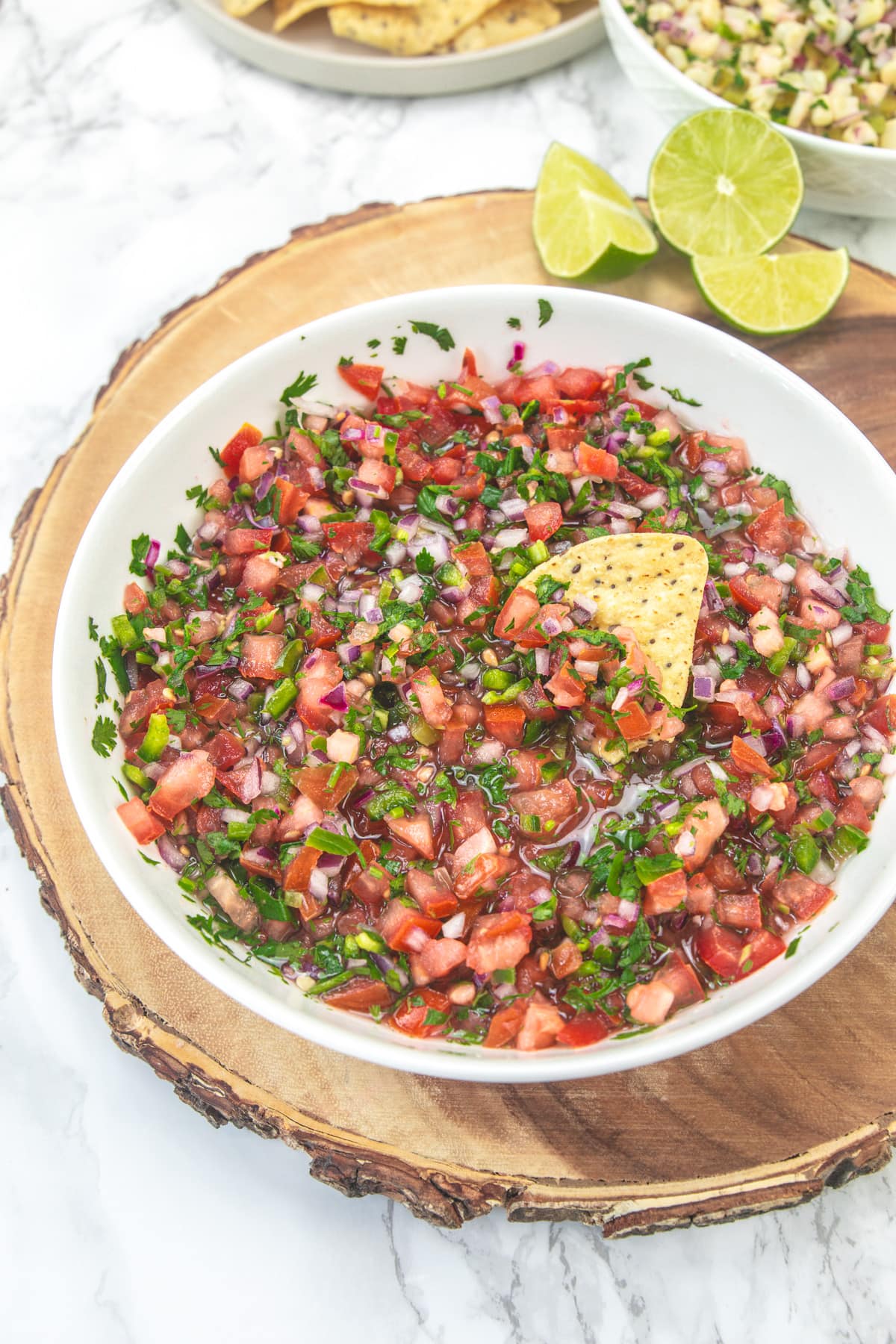 Scooping chipotle fresh tomato salsa with a tortilla chip.