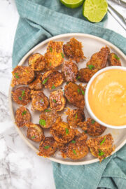 Parmesan crusted potatoes in a plate with a bowl of dipping sauce.