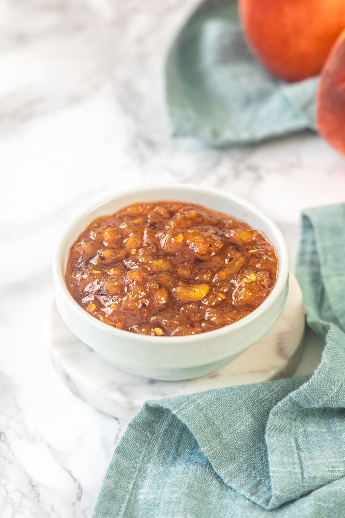 A bowl of peach chutney with napkin on the side.