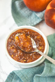 A spoonful of peach chutney taking from the bowl.