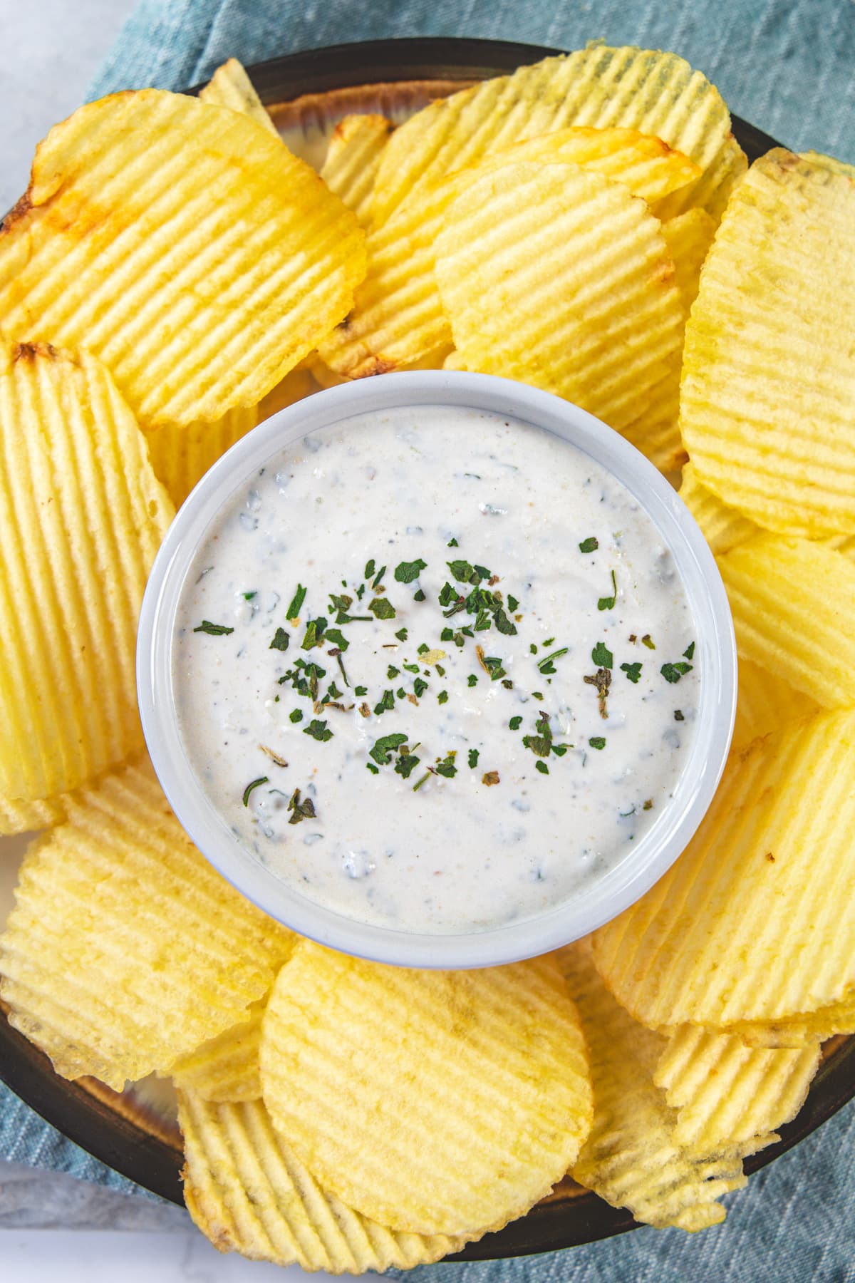 Sour cream dip garnished with dried herbs and served with potato chips.