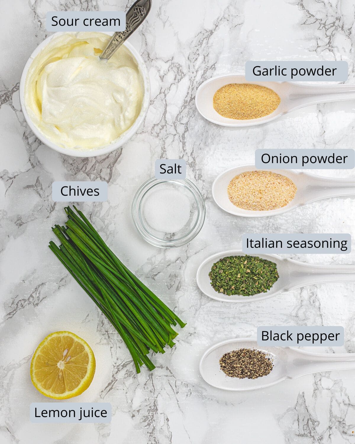 Sour cream dip ingredients in bowls and spoons with labels.