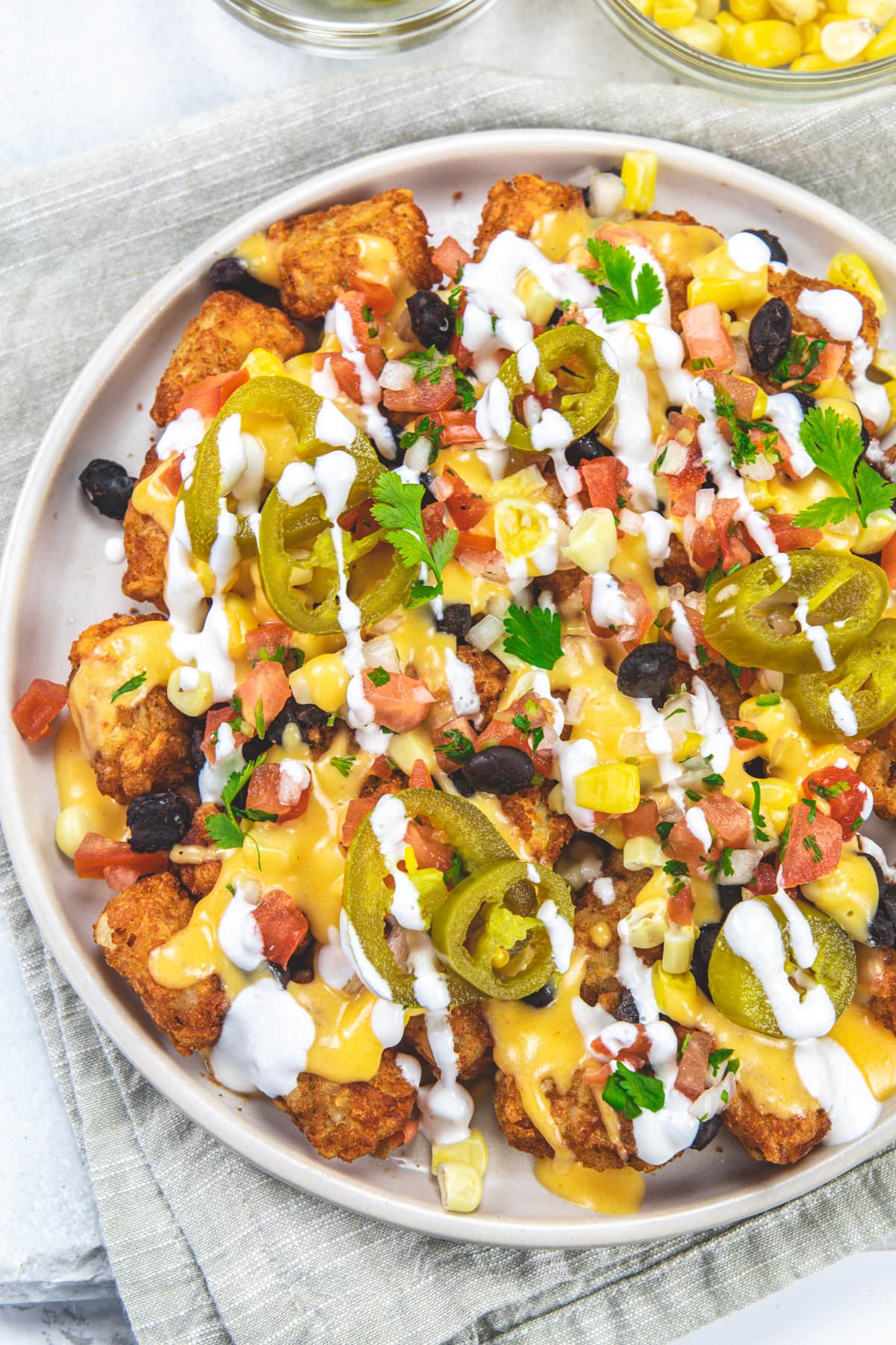 Tater tot nachos in a plate with a napkin under the plate.
