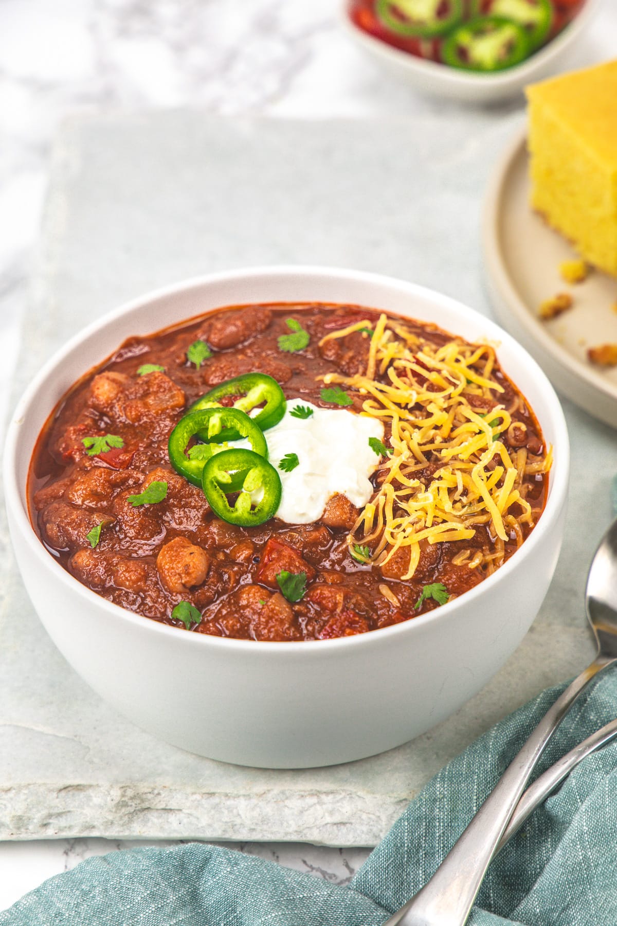 A bowl of vegetarian chili garnished with sour cream, jalapeno and cheese.