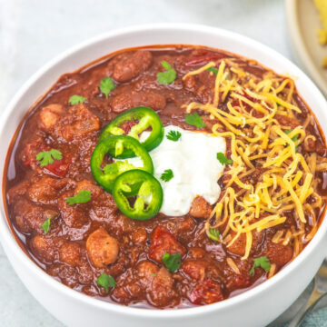 Instant pot vegetarian chili garnished with cheese, jalapeno and sour cream.