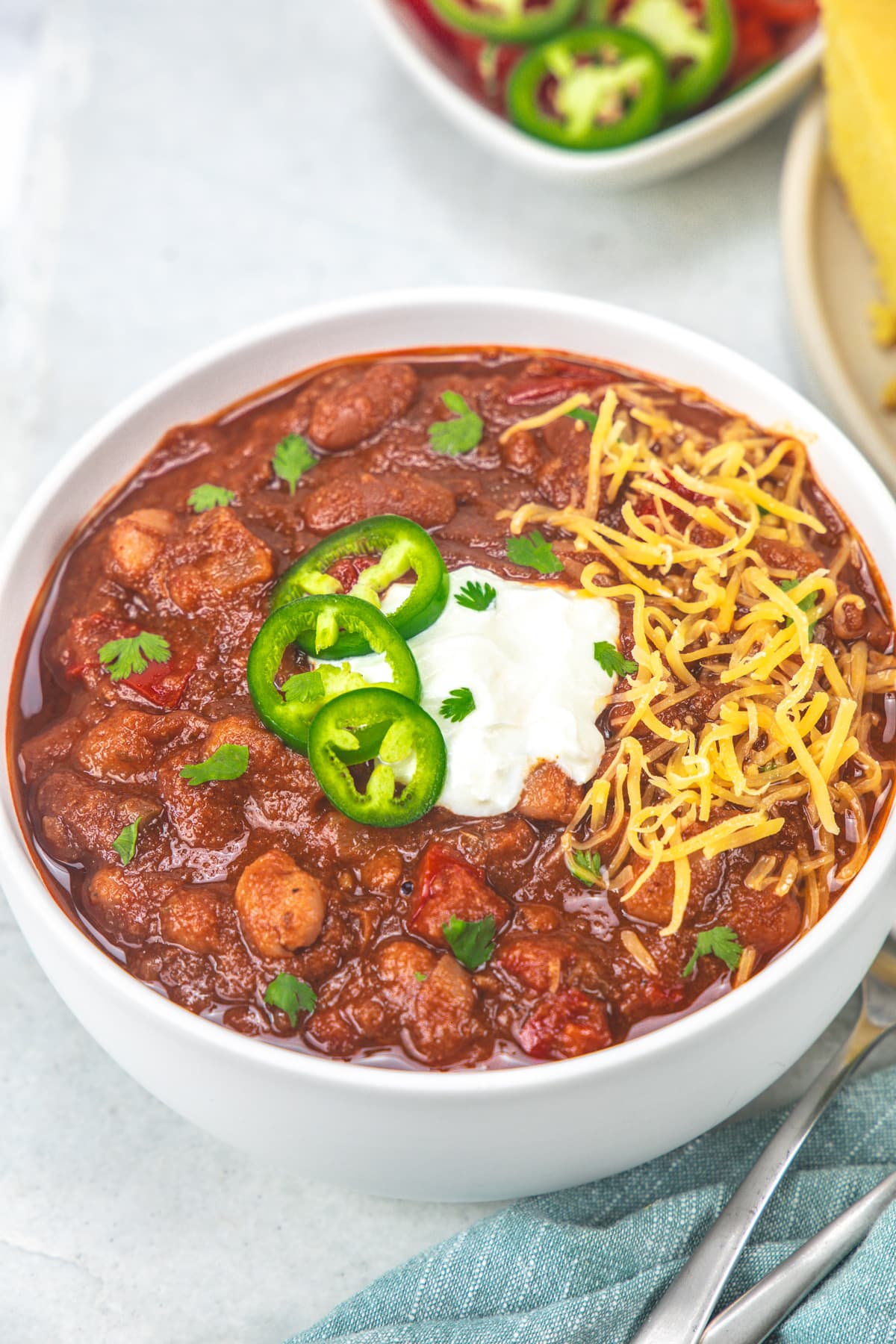Instant pot vegetarian chili garnished with cheese, jalapeno and sour cream.