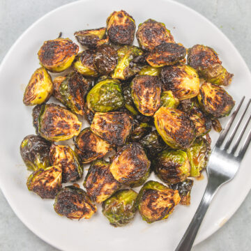 Roasted Brussels Sprouts with balsamic vinegar served in a white plate with fork.