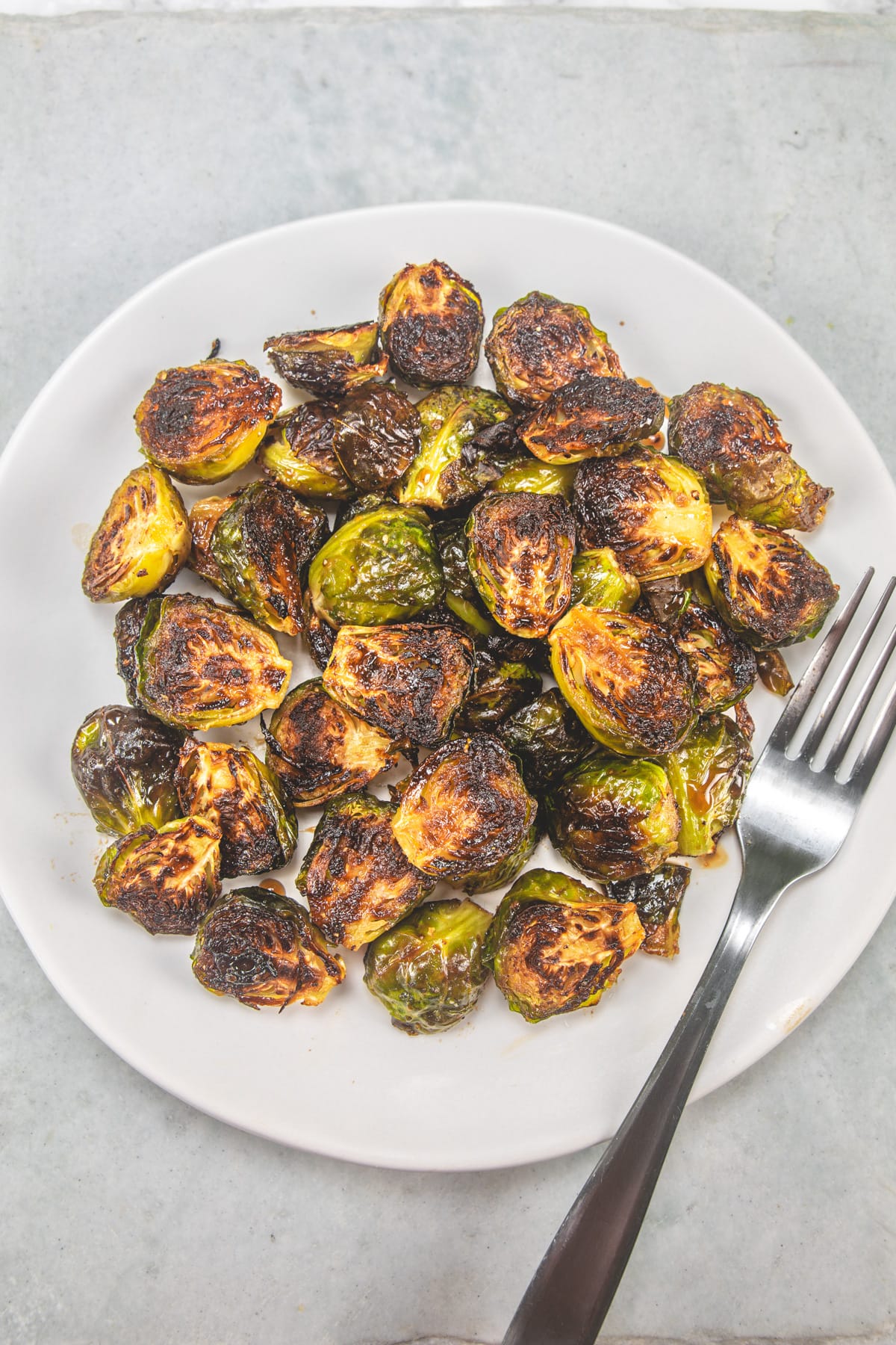 Roasted Brussels Sprouts with balsamic vinegar served in a white plate with fork.